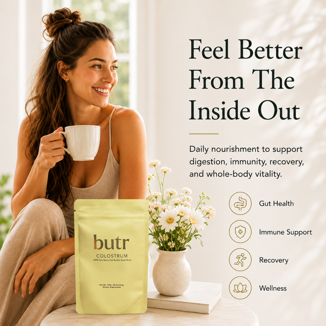 Woman holding a mug with 'butr' colostrum package and flowers on a table.